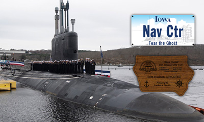 The USS Iowa SSN 797 partially submerged at the commissioning ceremony. Next to the sub, the license plate sign and walnut Iowa plaque are pictured.